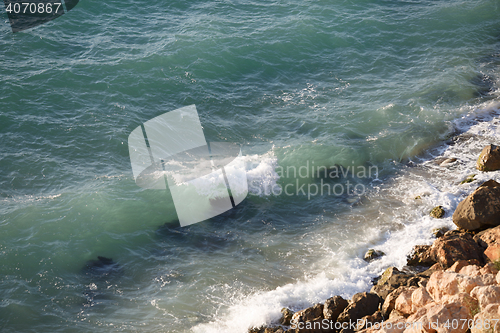 Image of Scenic shoreline with large boulders and clear turquoise sea waves