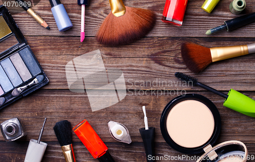 Image of Makeup cosmetics, brushes and other essentials on brown background