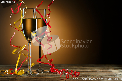 Image of Two glasses of champagne decorated with gold and red streamer