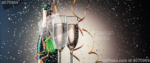 Image of Two wineglasses with champagne closeup, bottle, ribbons and snowflakes