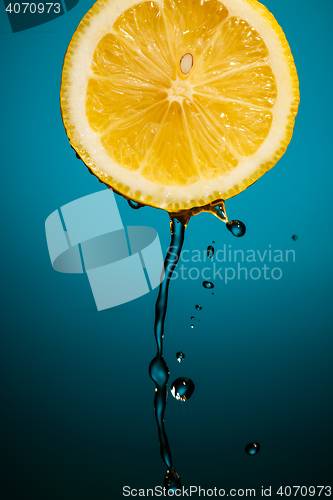 Image of Juicy lemon and drops of juice isolated on blue blackground in studio.