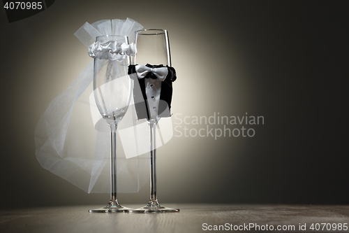 Image of Two empty wineglass dressed in veil and wedding tuxedo