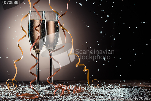 Image of Romantic image of two glasses with sparkling champagne and ribbons