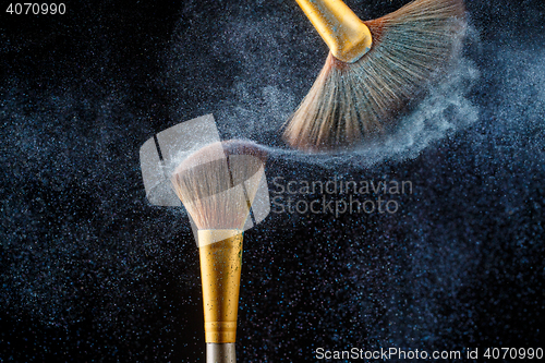 Image of Thick professional brushes making blue powder cloud on black background