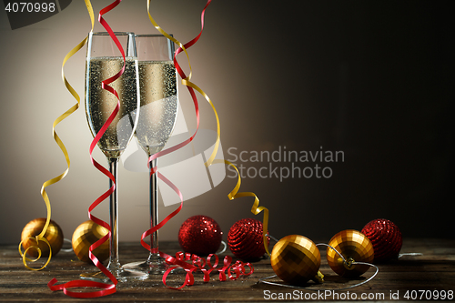 Image of Two glasses of champagne with bubbles and decorative Christmas balls