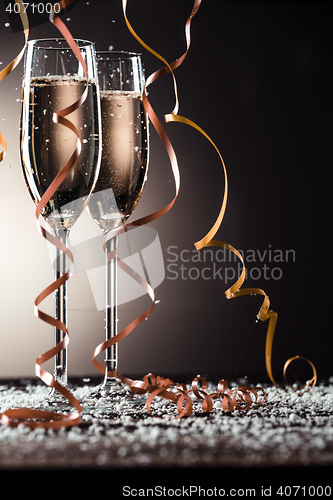 Image of Champagne glasses with ribbons and snowflakes on dark background