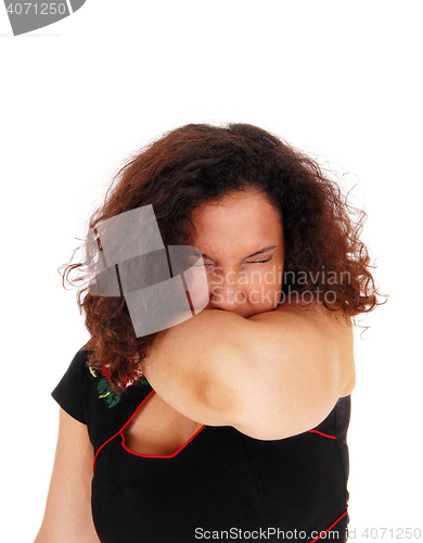 Image of Sneezing woman with arm over mouth.