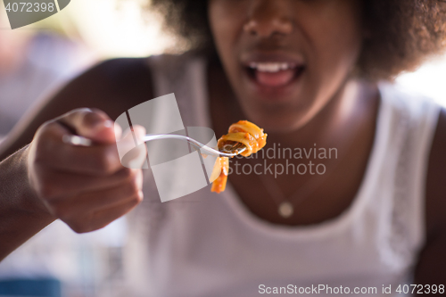 Image of a young African American woman eating pasta