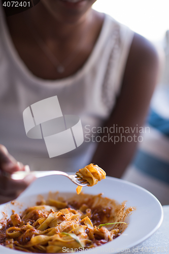 Image of a young African American woman eating pasta