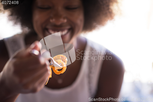 Image of a young African American woman eating pasta