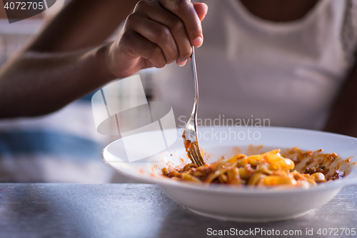 Image of a young African American woman eating pasta