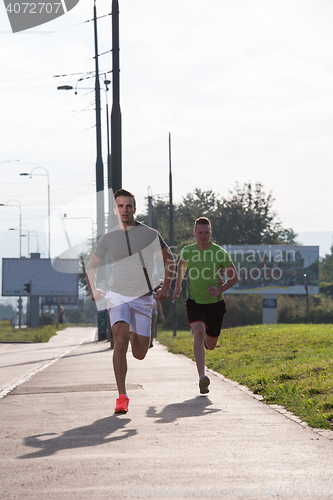 Image of Two young men jogging through the city