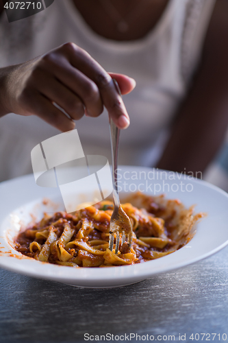 Image of a young African American woman eating pasta