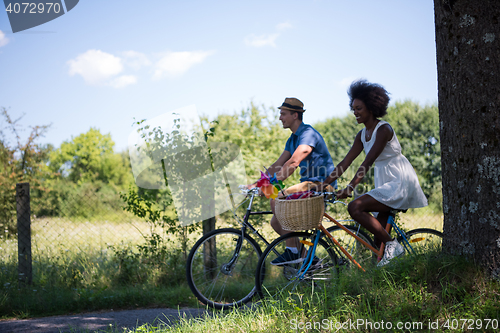 Image of Young multiethnic couple having a bike ride in nature