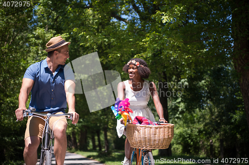 Image of Young multiethnic couple having a bike ride in nature