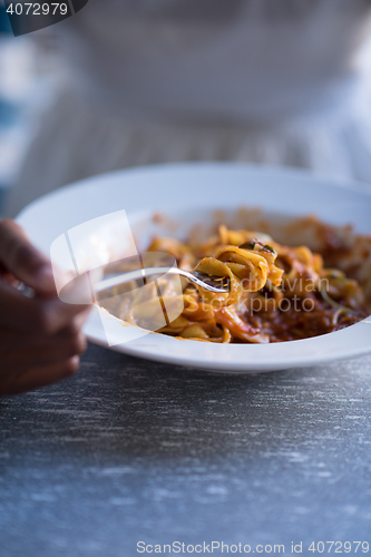 Image of a young African American woman eating pasta