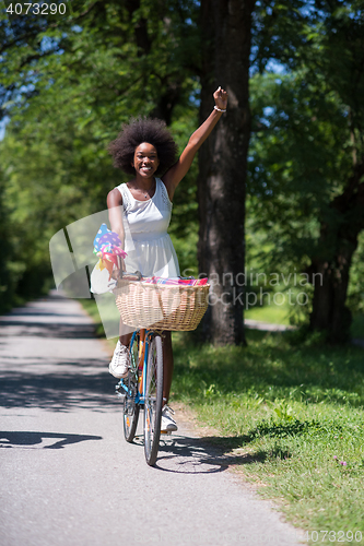 Image of pretty young african american woman riding a bike in forest