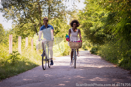 Image of Young multiethnic couple having a bike ride in nature