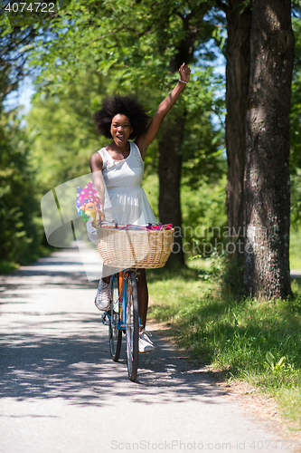 Image of pretty young african american woman riding a bike in forest