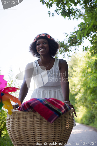 Image of pretty young african american woman riding a bike in forest