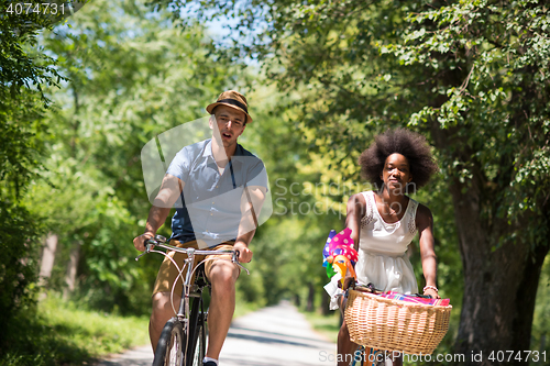 Image of Young multiethnic couple having a bike ride in nature