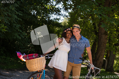 Image of Young multiethnic couple having a bike ride in nature