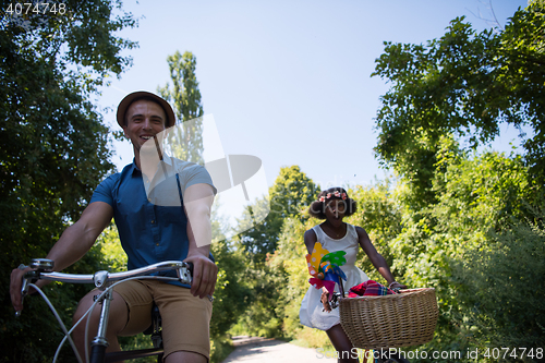 Image of Young multiethnic couple having a bike ride in nature