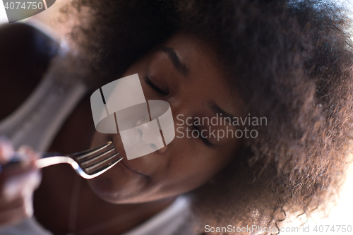 Image of a young African American woman eating pasta