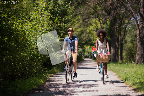 Image of Young multiethnic couple having a bike ride in nature