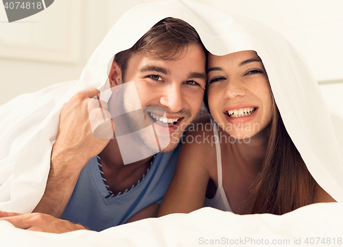 Image of Young couple playing under the sheets