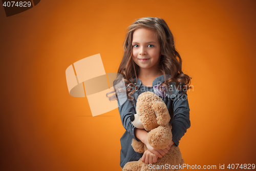 Image of The cute cheerful little girl on orange background