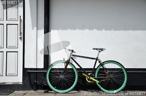 Image of Bicycle leaning and white painted brick wall