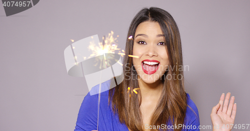 Image of Beautiful woman holding a burning sparkler