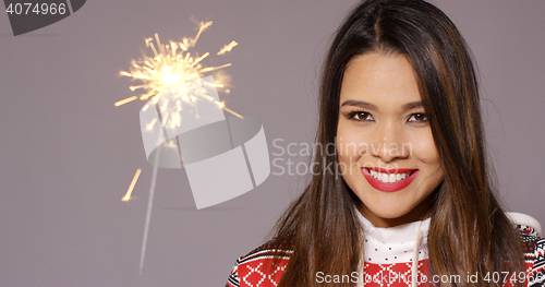 Image of Young woman celebrating Christmas with a sparkler