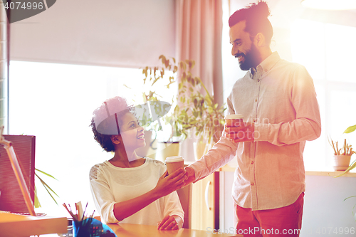 Image of happy man bringing coffee to woman in office