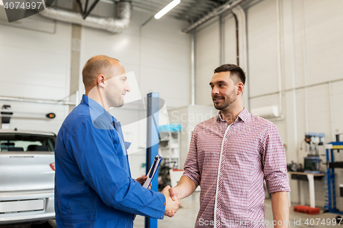 Image of auto mechanic and man shaking hands at car shop