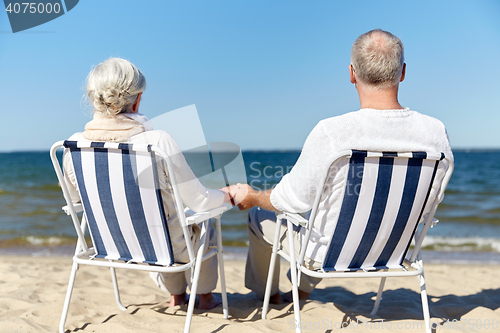 Image of senior couple sitting on chairs at summer beach