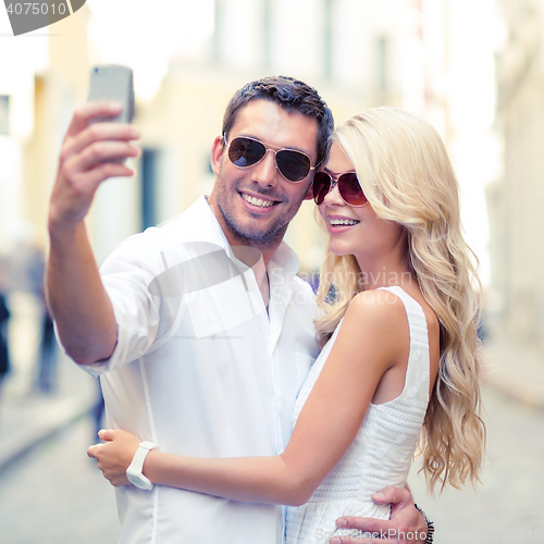 Image of smiling couple taking selfie with smartphone