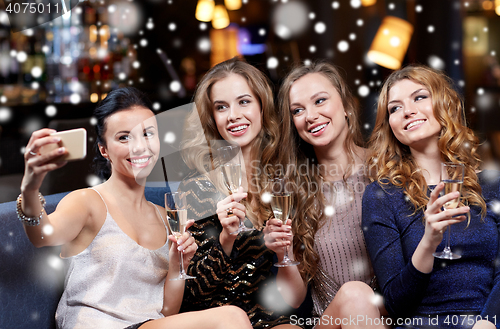 Image of women with champagne taking selfie at night club