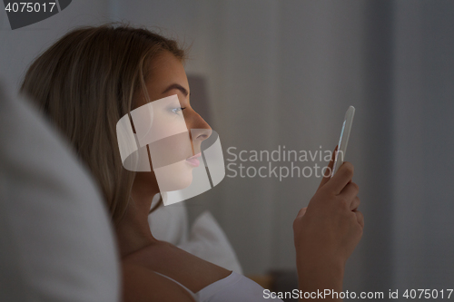 Image of young woman with smartphone in bed at night