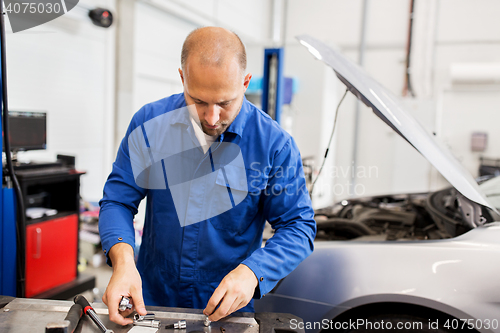 Image of mechanic man with wrench repairing car at workshop