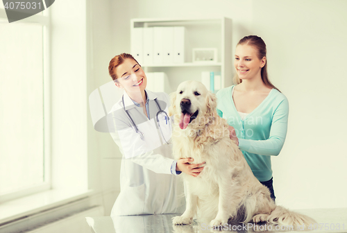 Image of happy woman with dog and doctor at vet clinic