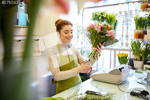 Image of smiling florist woman making bunch at flower shop