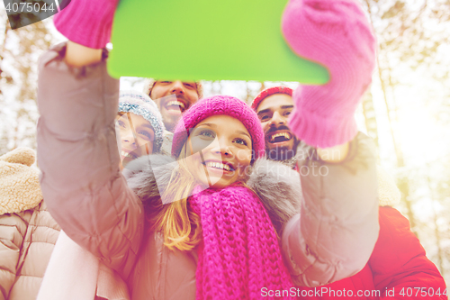 Image of smiling friends with tablet pc in winter forest