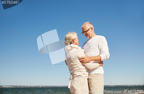 Image of happy senior couple hugging on summer beach