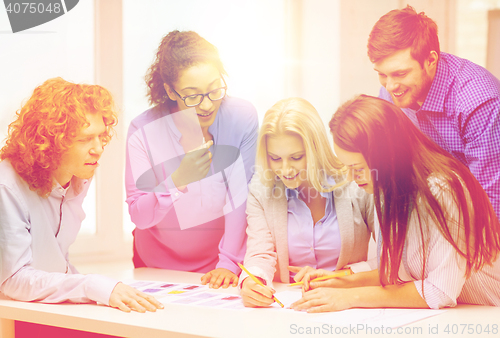 Image of smiling creative team looking over clothes designs