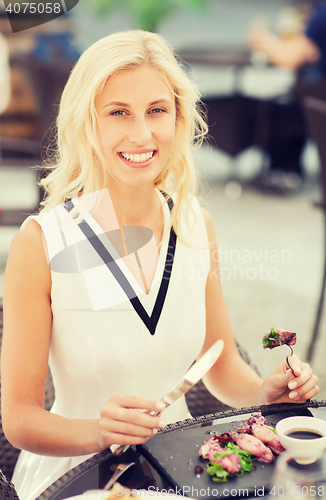 Image of happy woman eating dinner at restaurant terrace