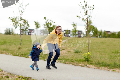 Image of happy father and little son walking outdoors