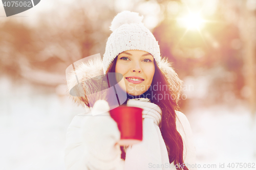 Image of happy young woman with tea cup outdoors in winter