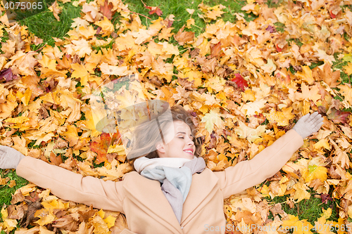 Image of beautiful happy woman lying on autumn leaves